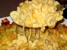 a white plate topped with macaroni and cheese covered in sauce being held by a fork