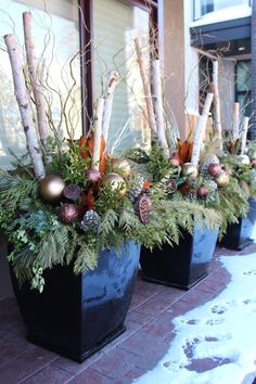 three black planters filled with christmas decorations