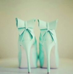 a pair of mint green high heels with bows on the toes and heel are sitting next to each other