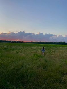 a person in a field flying a kite during the sun set with clouds and blue sky