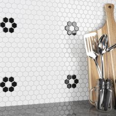 utensils and spoons sit on a cutting board in front of hexagonal tiles