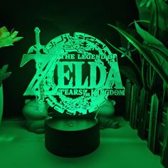 the legend of zelda lamp is glowing green in front of some plants and flowers