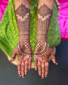 two hands with henna tattoos on them, one is showing off the intricate design