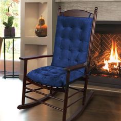 a rocking chair in front of a fireplace with a blue cushion on the seat and back