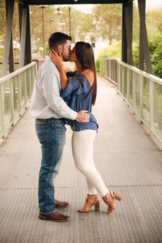 a man and woman kissing on a bridge