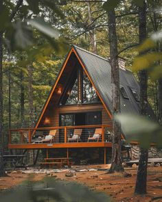 a frame cabin in the woods surrounded by trees and rocks, with chaise lounges on the deck