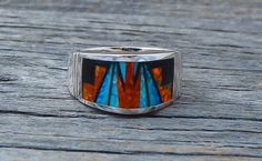 This band ring is handcrafted with Sterling Silver and beautifully inlaid with bright , dazzling, Fire Lab Opal and Onyx. As is seen in this work of art, the artist's talent is evident! It is a favorite due to the expertly clean cut geometric work, followed by the angular shape of the ring. This is that signature accessory that will compliment your wardrobe. We are proud to offer the David Rosales Collection of fine Native American Indian Jewelry. He has built a reputation for the finest inlaid Southwestern Style Rings With Inlay As Gift, Southwestern Style Rings With Inlay For Gift, Unique Multicolor Rings With Polished Finish, Artisan Multicolor Rings With Inlay, Artisan Multicolor Inlay Rings, Unique Sterling Silver Opal Inlay Ring, Unique Sterling Silver Opal Ring With Inlay, Unique Opal Ring With Inlay For Gift, American Indian Jewelry