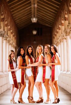 a group of women standing next to each other holding onto red and gold sashes