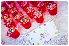 red plastic cups filled with sprinkles on top of a white doily