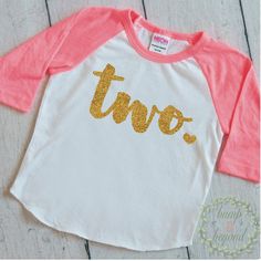 a white and pink shirt with the word three printed on it's front in gold glitter