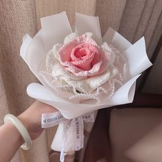 a person holding a white and pink flower in their left hand with a name tag on it