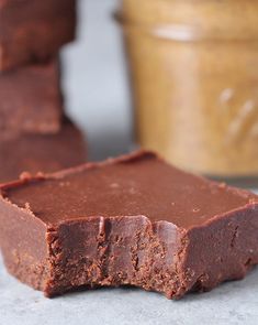 chocolate fudge brownies stacked on top of each other with peanut butter in the background