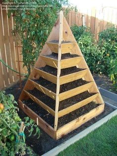 a wooden pyramid shaped planter filled with dirt