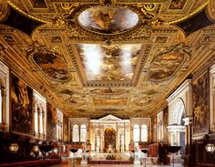 an ornately decorated room with gold and white paint on the ceiling, along with chairs and tables