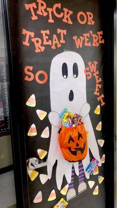 a trick or treat door decorated with candy and a ghost holding a jack - o'- lantern