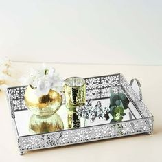 a silver tray with flowers and two candles on the table next to it is a gold vase