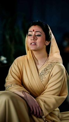 a woman sitting on the ground with her eyes closed and wearing a yellow sari