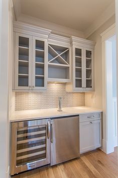 an empty kitchen with stainless steel appliances and white cupboards on the wall, along with hardwood flooring