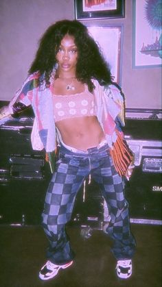 a woman standing in front of a piano wearing plaid pants and a cropped top