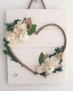 a heart shaped sign with flowers and leaves hanging on a rope hanger in the shape of a heart