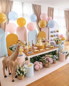 a giraffe is standing in front of a table with balloons and flowers on it