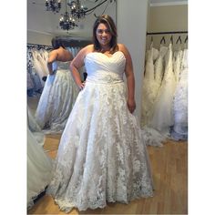 a woman is standing in front of some wedding gowns and posing for the camera