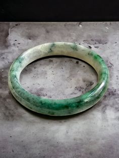 Our 'Earths' Bangle Bracelets are all one-of-one pieces; handpicked from the best parts of a Jadeite Rough stone. The Burmese A-Jadeite is completely untreated, un-enhanced. Each Bangle Bracelet has unique marbling and color hues, making each one truly unique. Certification available for an additional cost.  Ref: A1EBJBB08805000 Materials: 43.00g Burmese A-Jade Dimensions: 70.5 x 70.5 x 12.7 (Inner Diameter 56mm) Gross Weight: 43.00g Carved Jade Bangle Bracelet, Jade Gemstone Bangle Jewelry, Luxury Bangle Bracelet With Natural Stones, Carved Jade Round Bracelets, Carved Jade Bracelets, Green Carved Bangle Bracelet, Green Carved Bangle Bracelets, Jade Gemstone Bangle Bracelet, Spiritual Carved Round Bracelets