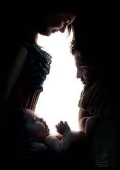 a woman holding a baby in her arms while looking at the light coming through it