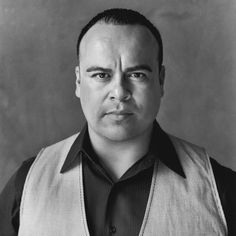 a black and white photo of a man wearing a vest