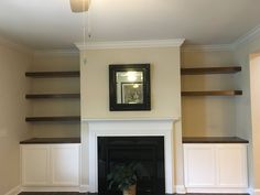 an empty living room with built - in shelves and a fireplace surround by a potted plant