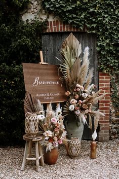 a wooden sign sitting on top of a table next to vases filled with flowers