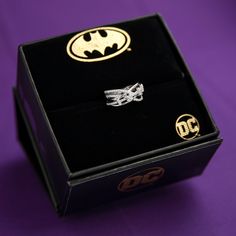 two rings in a black box on a purple surface with the batman symbol painted on it