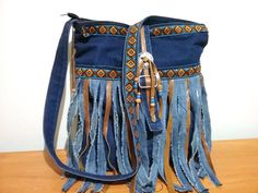 a blue purse with fringes and beads on the inside is sitting on a wooden table