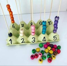 an egg carton filled with colorful beads and wooden skewers