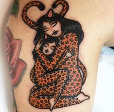 a woman and child tattoo on the back of her arm, with an orange leopard print