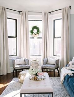 a living room with blue couches and white drapes on the window sill