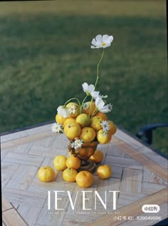 a vase filled with lemons and daisies on top of a wooden table outside