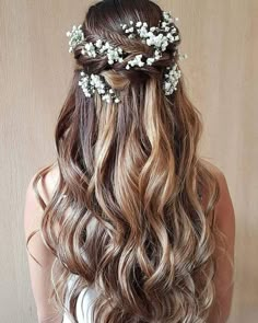 the back of a woman's head with long wavy hair and flowers in her hair