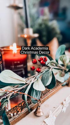 candles and greenery on a table with the words dark academy christmas decor