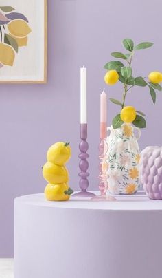 there is a vase with lemons and candles on the table next to each other