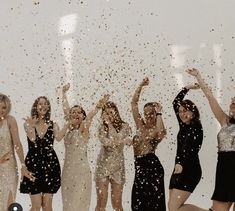 a group of women standing next to each other with confetti in the air