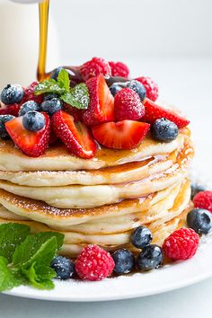 a stack of pancakes topped with berries and syrup