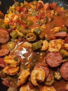 a skillet filled with shrimp, sausage and vegetables