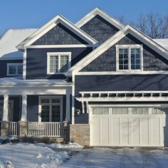 a house that is covered in snow and has two garages on the side of it