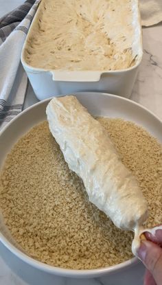 someone is dipping something into a bowl of rice with a spoon on the side and another dish in the background