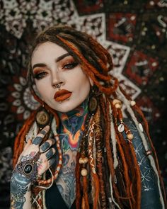 a woman with dreadlocks and tattoos on her face is posing for the camera