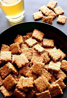 a bowl filled with crackers next to a glass of beer