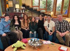 a group of people sitting on top of a couch in a living room next to each other