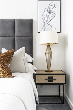 a bedroom with a bed, nightstand and art on the wall above it's headboard