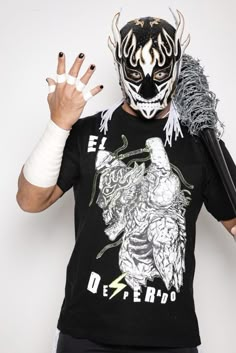 a man wearing a wrestling mask and holding two hands in front of his face,